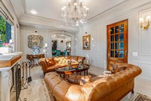 a living room with leather furniture and a chandelier at SaffronStays Naiintara in Nainital