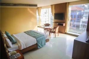 a bedroom with a bed and a table and a window at HOTEL APOLLO GRAND A UNIT OF SATYAM ASSOCIATES in Guwahati