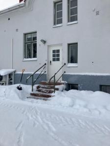 una casa con nieve en el suelo delante de ella en Vanha Kanttorila ,Huone B pohjakerroksessa, en Lovisa
