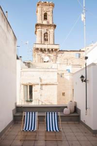 2 sedie sedute su un balcone con torre dell'orologio di Casa Vita Lenta by Momò Apulia a Monopoli