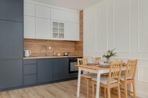 a kitchen with white cabinets and a wooden table and chairs at Cozy Apartment Orawska with Balcony by Renters in Krakow