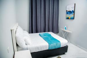 Schlafzimmer mit einem Bett mit weißer und blauer Bettwäsche in der Unterkunft Modern Village Apartments in Chipata