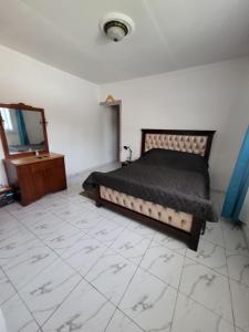 a bedroom with a bed and a dresser and a television at RESIDENCE LA VARENNE, DSCHANG in Dschang