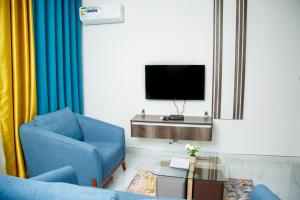 a living room with a blue chair and a tv at Modern Village Apartments in Chipata