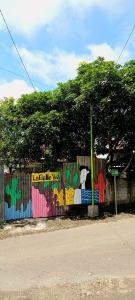 a fence with graffiti on it next to a street at La Belle Vie Homestay in Banyuwangi