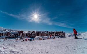 a person on skis in the snow in front of a resort at New Gudauri Twins in Gudauri