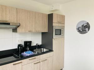 una cocina con armarios de madera y fregadero en Nicolette Apartments, en Katwijk aan Zee