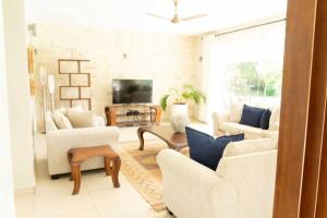 a living room with white furniture and a tv at The Four Palms in Kilifi