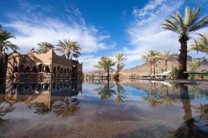 a pool of water with palm trees and a building at Lodge Hara Oasis in Agdz