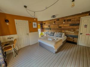 a bedroom with a bed and a wooden wall at The White Horse Hotel in Leiston