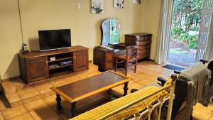 a living room with a tv and a table at Anri Guesthouse in Bloemfontein