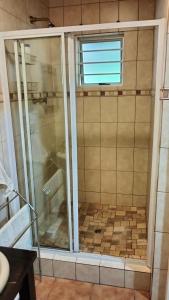 a shower with a glass door in a bathroom at Anri Guesthouse in Bloemfontein +49 photos