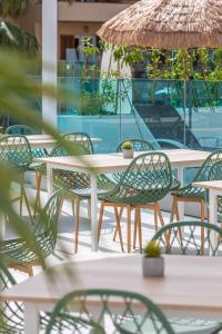 MarSenses Rosa del Mar Hotel & Spa في بالمانوفا: مجموعة طاولات وكراسي مع مظلات على الفناء