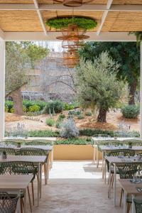 ein Restaurant mit Tischen und Stühlen und einen Garten in der Unterkunft MarSenses Rosa del Mar Hotel & Spa in Palmanova