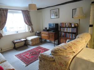 een woonkamer met een bank en een tv bij River Cottage in Tewkesbury