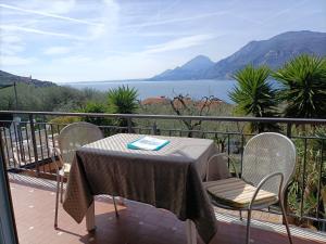 d'une table et de chaises sur un balcon avec vue sur l'eau. dans l'établissement Appartamenti Casa Nina, lago,montagne, uliveti, à Brenzone