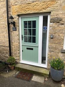 a green door on a stone house with plants at Brewers Den a Beautiful 1-Bed Apartment in Masham in Ripon