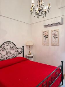 una camera con letto rosso e lampadario a braccio di Resort Romano in Trulli ad Alberobello