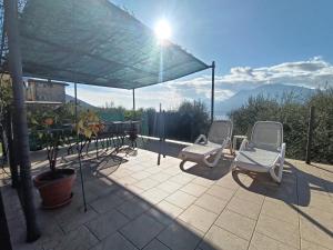 2 chaises assises sur une terrasse sous un auvent dans l'établissement Appartamenti Casa Nina, lago,montagne, uliveti, à Brenzone