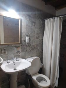 a bathroom with a white toilet and a sink at Cabañas Alicia in San Rafael