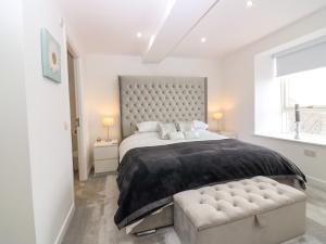 a white bedroom with a large bed and a bench at Craignure in Banff