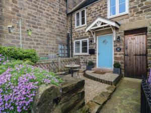 a brick house with a wooden door and flowers at Clematis Cottage in Belper