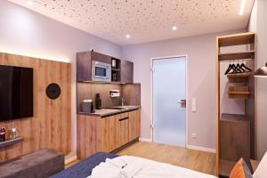a bedroom with a bed and a kitchen with a microwave at XZLLENZ - Modern, Neu, Luxus, Frei-Parken, U-Bahn in Nürnberg