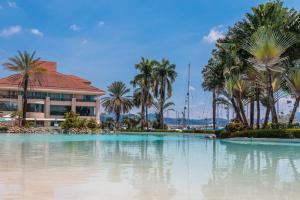 a swimming pool with palm trees and a building at The Subic Bay Yacht Club, Inc. in Olongapo