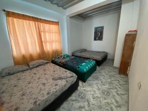 Duas camas num quarto com uma janela e uma saia-cama em Hotel CAB DE TOLU em Tolú