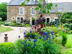 a garden in front of a stone house with flowers at Demeure du Porzou in Yvias