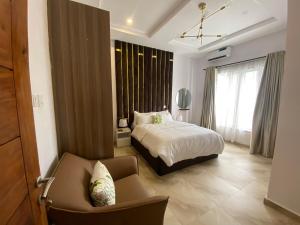 een slaapkamer met een bed, een stoel en een bank bij Absl Luxury Apartments in Lekki