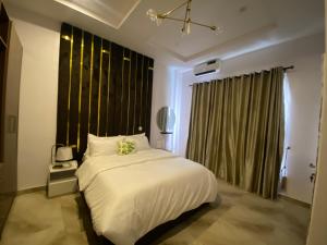 een slaapkamer met een wit bed en een groot raam bij Absl Luxury Apartments in Lekki