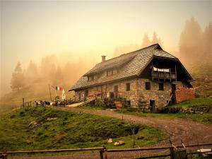 uma casa velha no topo de uma colina no nevoeiro em Thurners urige Frühstücks Pension em Würmlach