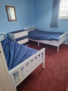 two beds in a room with blue walls at great holidays hemsby in Hemsby