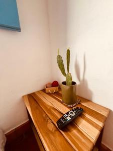 巴里查拉的住宿－Casa Quintanilla Barichara，一只手仙人掌坐在木桌边的遥控器