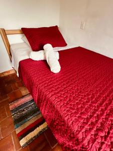 Una cama roja con dos toallas encima. en Casa Quintanilla Barichara en Barichara