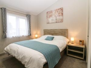 a bedroom with a large bed with a blue blanket at Woodpecker Lodge in Dunbar