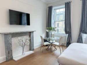a bedroom with a fireplace and a table with chairs at Hanover 71 Suites in Edinburgh