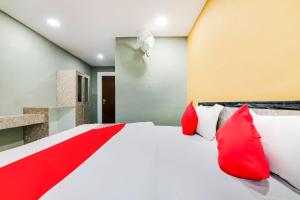 1 dormitorio con cama blanca y almohadas rojas en OYO Flagship Aadya Greens en Juhi Bari
