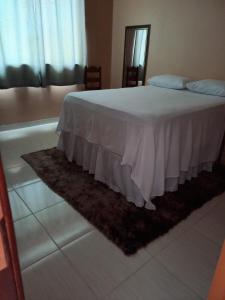 1 dormitorio con cama con colcha blanca y alfombra en Um lugar calmo e aconchegante, en Manaus