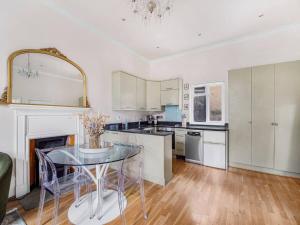 a kitchen with white cabinets and a glass table at Chic cosy Flat in Central London Pass the Keys in London