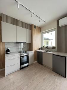 a kitchen with white cabinets and a stove top oven at Apartament Pileckiego 7b/15 in Suwałki