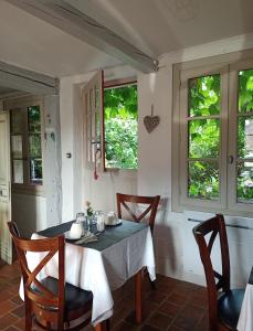 comedor con mesa, sillas y ventanas en Les chambres d'hôtes Le Val d'Honfleur, en Équemauville