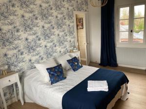 1 dormitorio con 1 cama con papel pintado azul y blanco en Les chambres d'hôtes Le Val d'Honfleur, en Équemauville