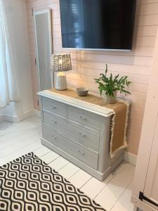 a dresser in a room with a tv on a wall at The Seawitch - harbourside apartment in Mousehole