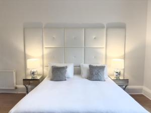 een slaapkamer met een groot wit bed met 2 lampen bij Hanover 71 Suites in Edinburgh
