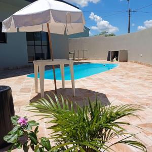 um guarda-chuva branco sentado ao lado de uma piscina em Recanto Shalom desativado em São Carlos