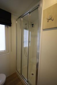 a glass shower in a bathroom with a toilet at Mobilheim Summer Lounge Appartment I in Borgdorf-Seedorf