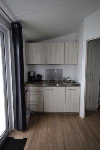 cocina con armarios blancos y suelo de madera en Mobilheim Summer Lounge Appartment I en Borgdorf-Seedorf