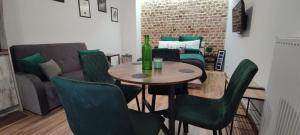 ein Wohnzimmer mit einem Tisch und grünen Stühlen in der Unterkunft Prosta Butelkowa in Toruń